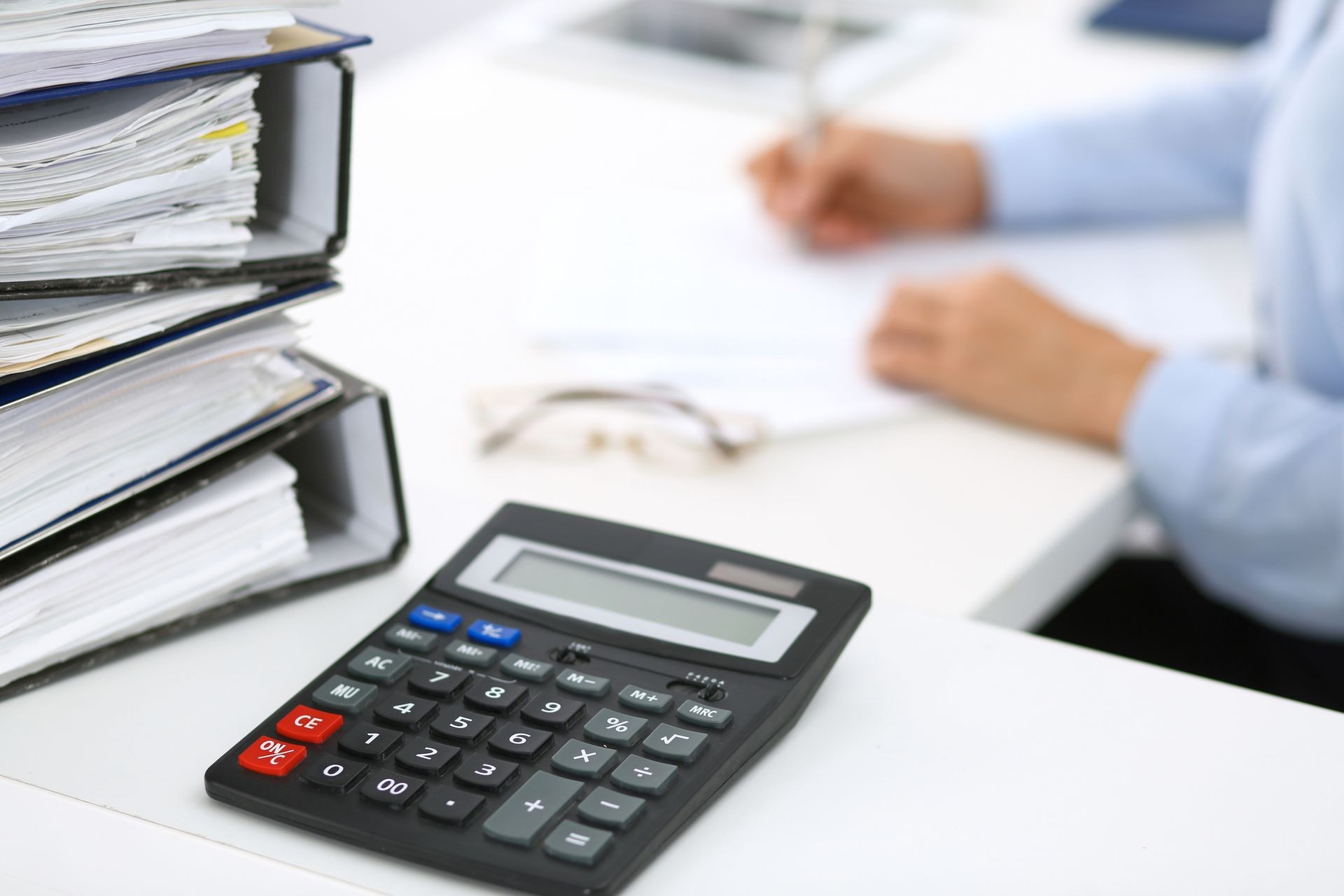 Calculator and binders with papers are waiting to be processed by business woman or bookkeeper back in blur. Internal Audit and tax concept Calculator and binders with papers are waiting to be processed by business woman or bookkeeper back in blur. Internal Audit and tax concept